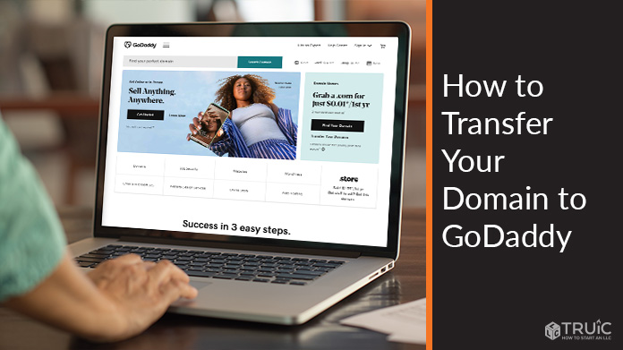 Person working on computer with GoDaddy homepage on screen.