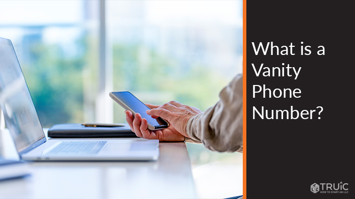 Person using cell phone at computer.
