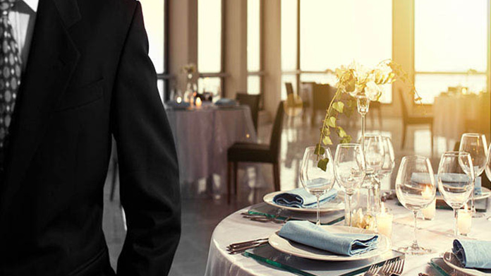 A person in a suit in front of an upscale dining table