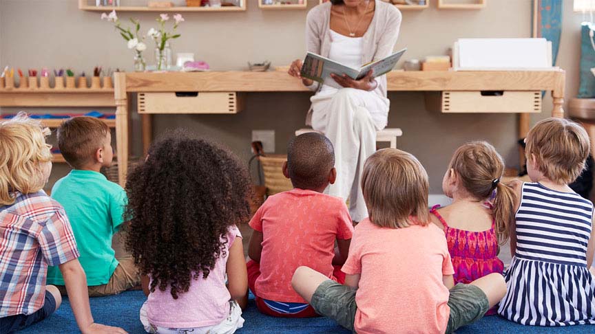 teacher reading a childrens book to her classroom