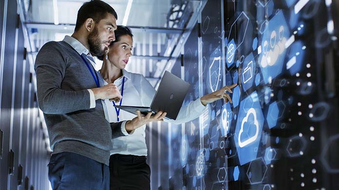 Two people looking at a row of servers
