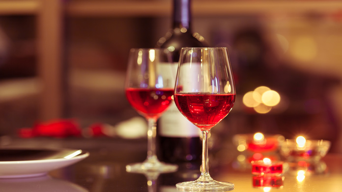 a table set up for a date with two glasses of red wine