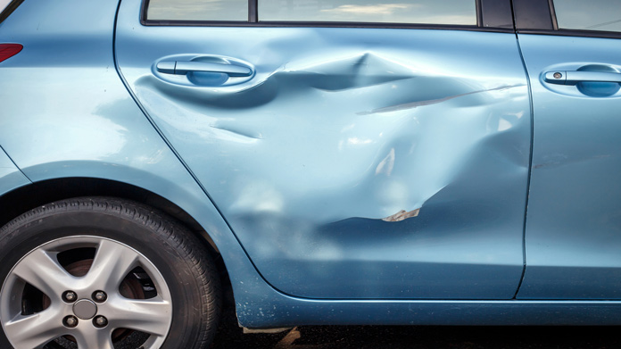 a close up of a large dent on a backseat passenger car door