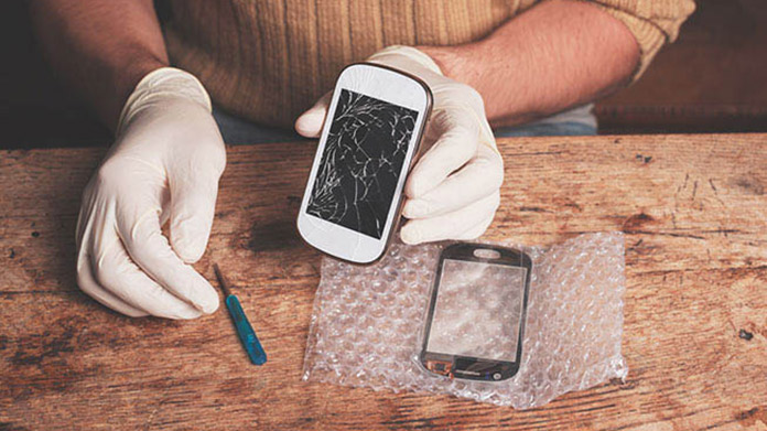 Person wearing gloves and repairing a cell phone