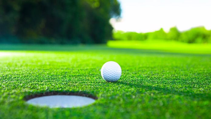A golf ball on the green near a hole