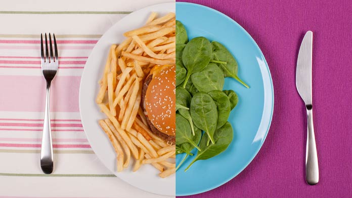 A split plate split in half, one side with spinach and the other with a burger and fries