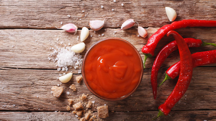 hot sauce in a glass bowl with hot peppers and garlic