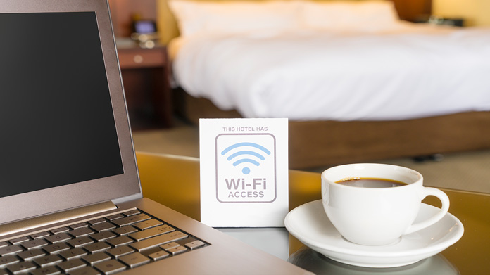 A laptop, coffee, and wi-fi access card on a hotel room table