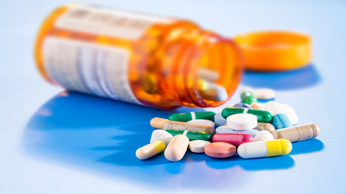 A pill bottle on its side with colorful pills spilling out