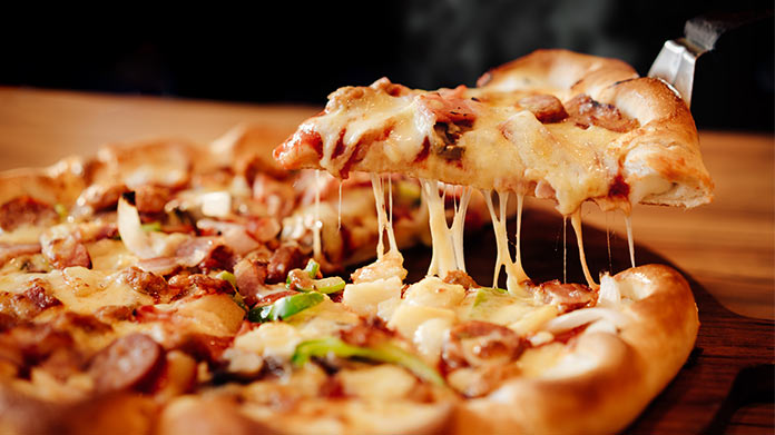 A slice of pizza being pulled from the full pizza