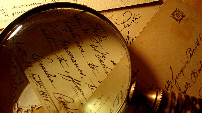 a magnifying glass on a pile of old-fashioned letters