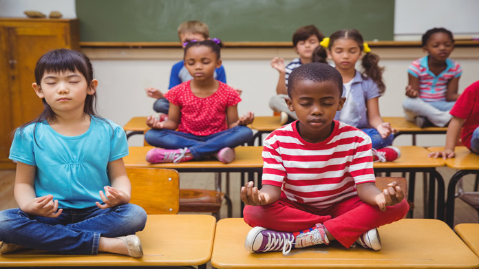 Kids sitting on desks meditating