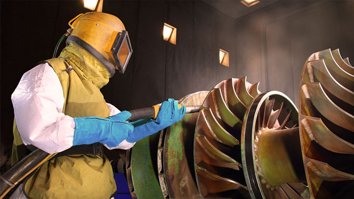 A person sandblasting a machine