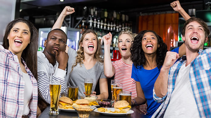 A group of sports fans cheering around a sports bar table