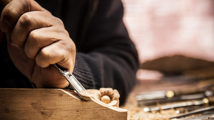 man using tools to sculpt a design on wood