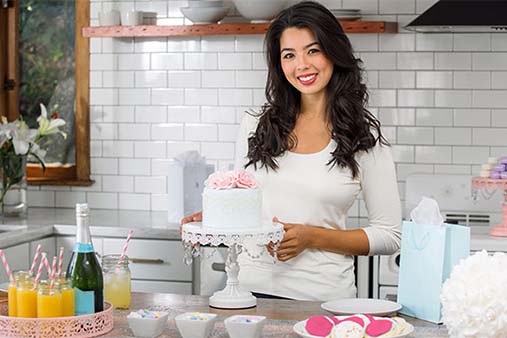Lady smiling with a decorated cake.