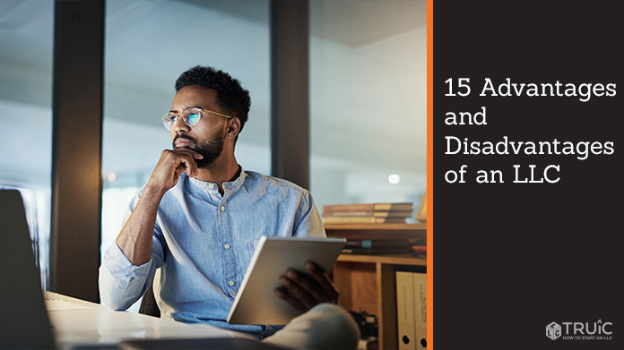 Man holding a notebook in front of a computer screen.