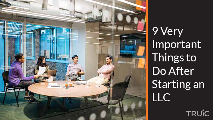 Four business people meeting in a conference room with post it notes on the window.