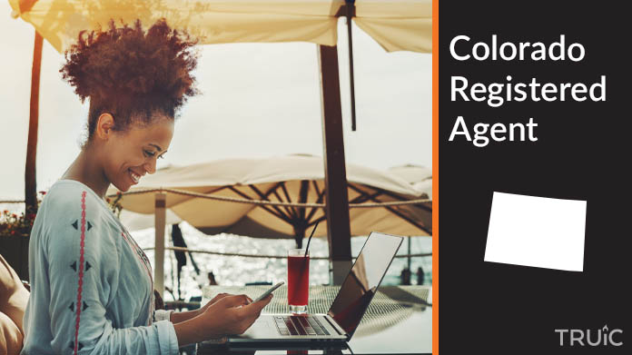 A person happily working remotely at a beach while their registered agent service takes care of business