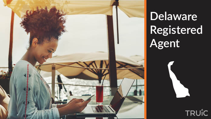 A person happily working remotely at a beach while their registered agent service takes care of business