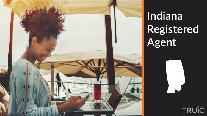 A person happily working remotely at a beach while their registered agent service takes care of business