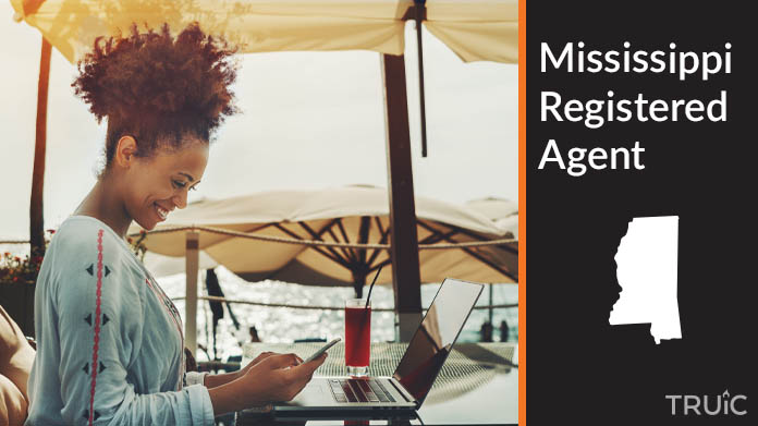 A person happily working remotely at a beach while their registered agent service takes care of business