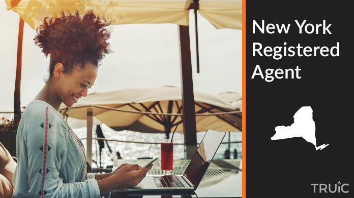 A person happily working remotely at a beach while their registered agent service takes care of business