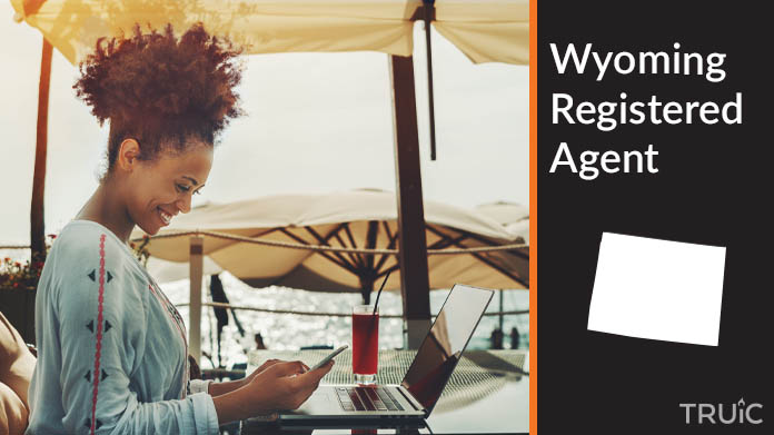 A person happily working remotely at a beach while their registered agent service takes care of business