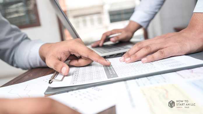 Two businesspeople examining papers on a desk, discussing capital expenditures and business expenses